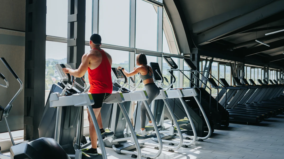 Personas haciendo cardio en máquinas elípticas dentro de un gimnasio
